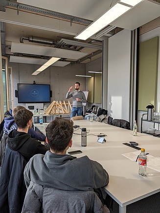 Foto eines Seminarraumes bei ZÜBLIN Timber mit Personen die auf einen großen Bildschirm schauen