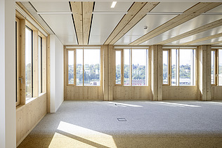 Interior photo of an empty office space. Glulam beams, wood-concrete composite ceiling.