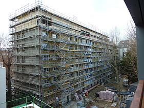 Foto eines mehrgeschossigen Gebäudes im Rohbaustand mit Aufstockung aus Holz.