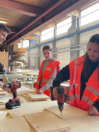Foto von einem Mann und zwei Mädchen, die mit Akkuschrauber und Holz arbeiten.