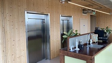 Photo of an interior of the Black and White office in London. You can see wooden surfaces and a kitchenette.