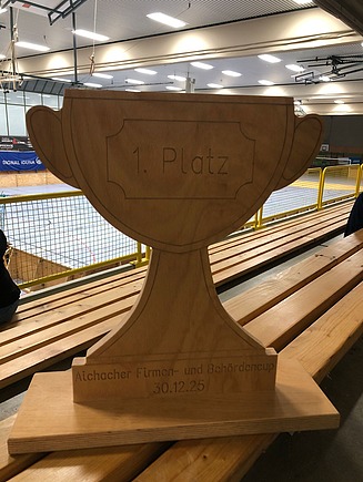 Foto eines Holzpokals. Firmen- und Behördencup in der Turnhalle. Fußballspiel.