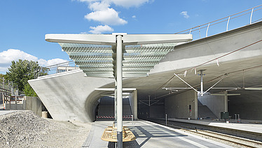 Foto von der Haltestelle Staatsgalerie in Stuttgart. Man sieht Zugschienen und Betonschalungen und einen  überdachten Wartebereich.