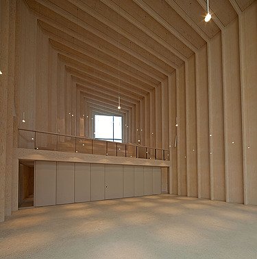 Photo of the interior of the Immanuel Church in Cologne. You can see an empty, high room with wooden walls and a wooden ceiling.