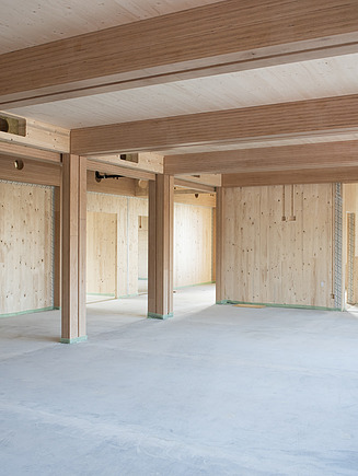 Foto eines Innenraumes der Baustelle Schule am Hang. Zu sehen sind LENO-Brettsperrholzoberflächen und BauBuche-Stützen.