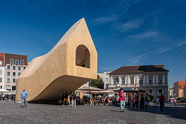 Foto des NEXT500-Pavillons auf dem Augsburger Marktplatz. Sie können ein modernes Holzgebäude sehen.