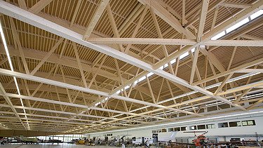 Photo of the Pilatus CH-Stans assembly hall. A large glulam roof construction can be seen.