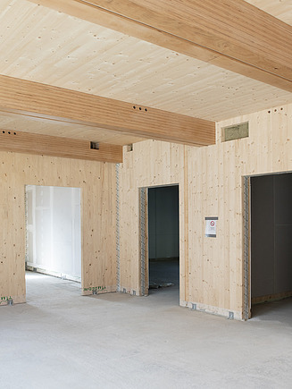 Photo of an interior of the construction site school on a slope. Many LENO cross-laminated timber surfaces can be seen.