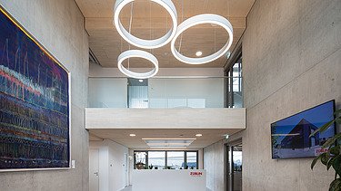 Photo of the modern office entrance area at ZÜBLIN Neu-Ulm. Concrete walls and wooden ceiling can be seen.