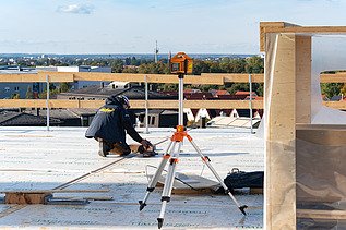 Foto der Montage des UmweltHauses in Nürnberg. Man sieht eine Person, die Messaufnahmen macht.