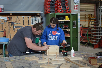 Photo of two people building a birdhouse in the ZÜBLIN Timber workshop.