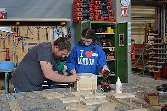 Photo of two people building a birdhouse in the ZÜBLIN Timber workshop.