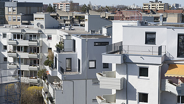 Foto eines mehrgeschossigen Gebäudes mit weißer Fassade. Aufstockung aus Holz.