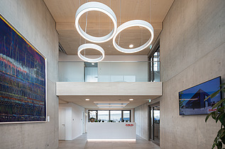 Photo of the modern office entrance area at ZÜBLIN Neu-Ulm. Concrete walls and wooden ceiling can be seen.
