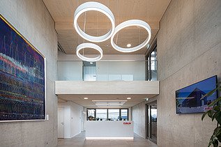 Photo of the modern office entrance area at ZÜBLIN Neu-Ulm. Concrete walls and wooden ceiling can be seen.