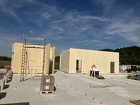 Baustellenfoto, auf dem die Montage der ersten Brettsperrholzelemente zu sehen ist.