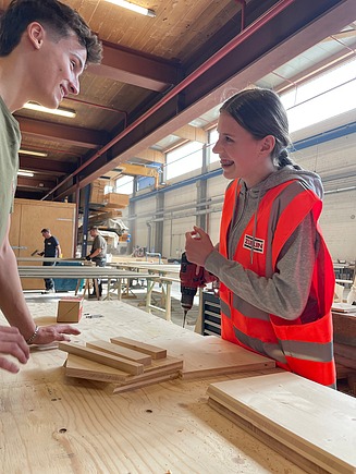 Photo of a man and a girl working with a cordless screwdriver and wood.