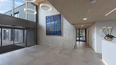 Photo of the modern office entrance area at ZÜBLIN Neu-Ulm. Concrete walls and wooden ceiling can be seen.