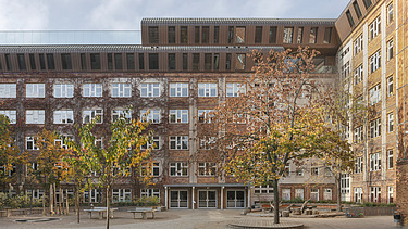Photo of the wooden extension to the Metropolitan School Berlin. You can see a large multi-storey building.