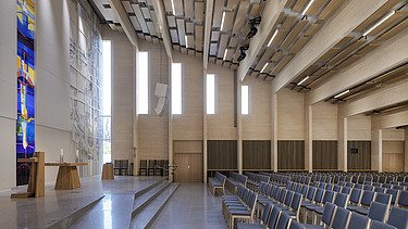 Photo of the interior seating of the Tau Kirke in Norway. You can see the wooden skeleton structure of the ceiling and wooden elements on the wall.