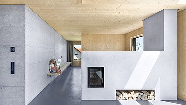 Foto eines modernen Holzhauses mit Holzfassade. Innenaufnahme Kaminzimmer. Holz- und Betonwände.