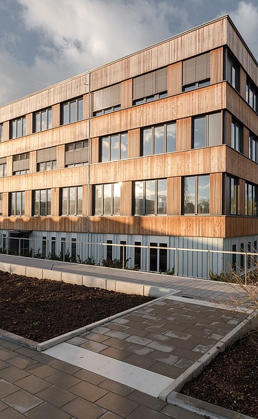 Bürogebäude Flexim Berlin Foto de Bürogebäudes Flexim Berlin von außen. Zu sehen ist ein großes Gebäude aus Holz mit Holzfassade und Flachdach.