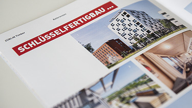 Foto der Innenseite der Image-Broschüre von ZÜBLIN Timber. Man sieht mehrere Gebäude aus Holz und die Überschrift Schlüsselfertigbau.