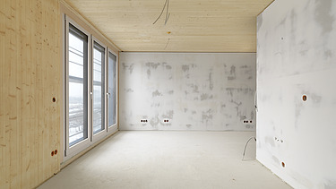 Foto des Gebäudes SKAIO Stadtsiedlung in Heilbronn. Man sieht einen Innenraum  mit Holzoberflächen und Betonwänden.