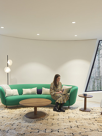 Innenraum des Maggie Center in London. Man sieht einen Wohnraum mit Couch und einer Frau darauf sitzen.