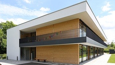 Foto eines Gebäudes aus Holz mit Flachdach.