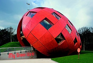 Foto eines rießigen, schrägliegenden Holzeis mit orangefarbiger Holzfassade und Fenstern.