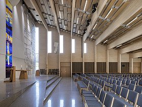 Photo of the interior seating of the Tau Kirke in Norway. You can see the wooden skeleton structure of the ceiling and wooden elements on the wall.