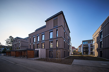 Foto eines mehrgeschossigen Wohngebäudes mit Holzfassade.