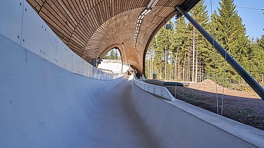 Foto einer Rodelbahn. Man sieht eine Holzüberdachung und nur einen Ausschnitt davon