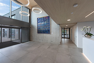 Photo of the modern office entrance area at ZÜBLIN Neu-Ulm. Concrete walls and wooden ceiling can be seen.