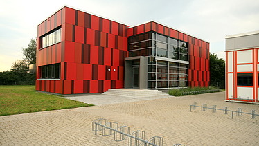 Foto einer Außenansicht der Einhardschule in Seligenstadt. Man sieht eine rote Fassade.