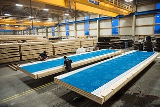 Photo of the ZÜBLIN Timber production facility. You can see large wooden elements with a blue weather protection film.