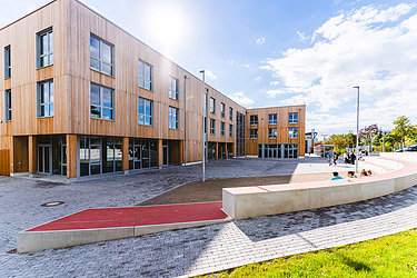 Foto der neuen Universität in Witten-Herdecke. Zu sehen ist ein großes Gebäude aus Holz und mit Holzfassade.