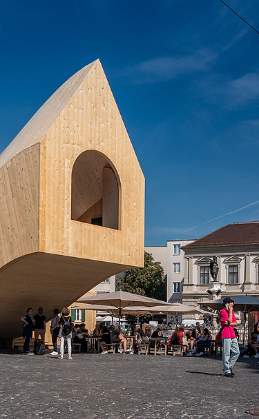 Foto des NEXT500-Pavillons auf dem Augsburger Marktplatz. Sie können ein modernes Holzgebäude sehen.
