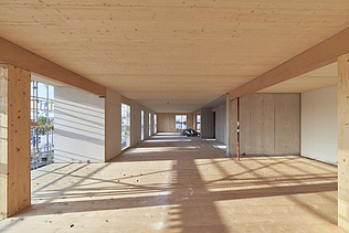 Innenaufnahme eines Gebäuderaumes aus Holz im Rohbaustand. Man sieht viele Holzoberflächen.