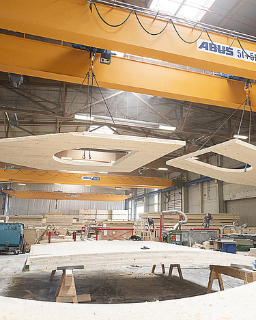 Production at the heart of ZÜBLIN Timber Photo of LENO cross-laminated timber elements on the crane in the ZÜBLIN Timber production hall.