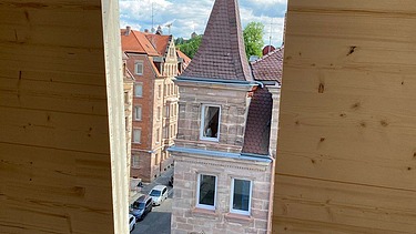 Photo of a LENO cross-laminated timber wall with a window. A church spire can be seen in it.