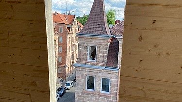 Photo of a LENO cross-laminated timber wall with a window. A church spire can be seen in it.