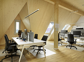 Additions, building in existing buildings. Project German Choir Center Berlin Photo of an interior shot of an office space. The sloping LENO cross-laminated timber walls and ceilings are clearly visible.