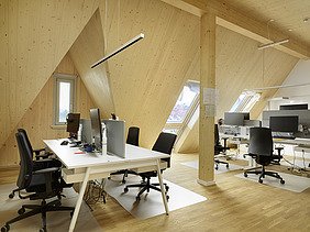 Photo of an interior shot of an office space. The sloping LENO cross-laminated timber walls and ceilings are clearly visible.