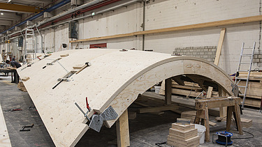 Foto einer Produktionshalle mit einer geschwungenen Holzschale