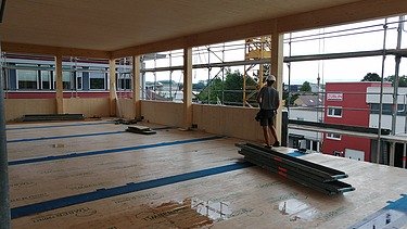 Foto eines Rohbaus aus Holz. Man sieht einen Innenraum der ersten Etage 