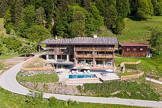Photo of a wooden hotel in the middle of the mountain landscape.