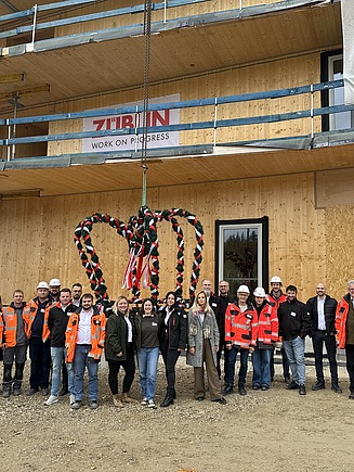 Aktuelles ZÜBLIN Timber Foto beim Richtfest Grünes Zentrum Landshut. Zu sehen ist ein Holzbau im Rohbau mit Menschen davor.