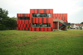 Foto einer Außenansicht der Einhardschule in Seligenstadt. Man sieht eine rote Fassade.